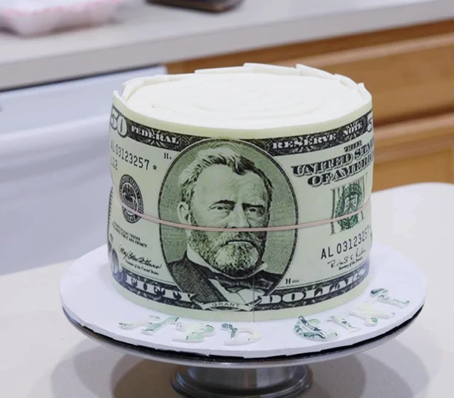 Money-themed birthday cake by Kakey Mae. A money-inspired wrap around a round cake with a clean white top.