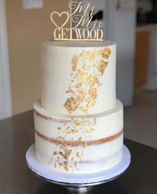 Gold leaf wedding cake by Kakey Mae. Two white tiers with gold accents and a personalized wedding topper.