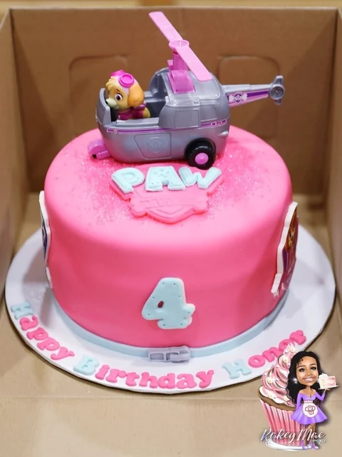 Pink character birthday cake by Kakey Mae. A bright pink cake with a character vehicle topper and personalized birthday details.