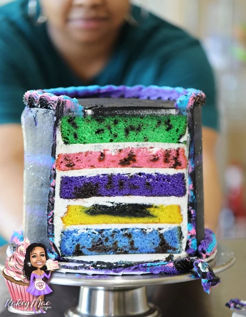 A rainbow inside by Kakey Mae. A cutaway view of colorful cake layers framed with purple and blue frosting.