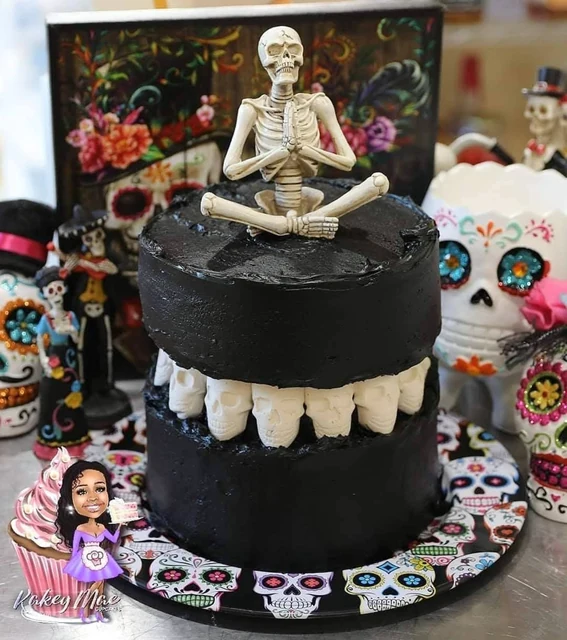 Skeleton celebration cake by Kakey Mae. Black tiers, ivory drip details, and a skeleton topper in a colorful party setting.