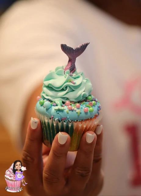 Mermaid cupcake close-up by Kakey Mae. A turquoise frosting swirl, pastel sprinkles, and a shimmering mermaid tail.