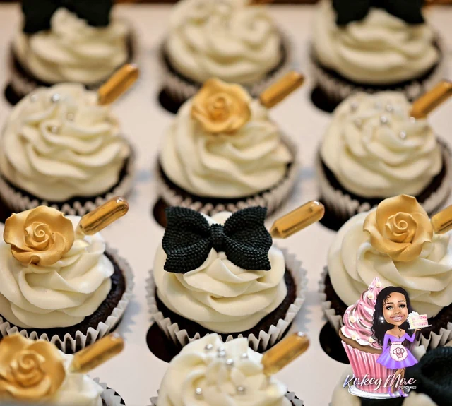 Black & gold occasion cupcakes by Kakey Mae. White frosting, gold roses, black bows, and little celebration details.