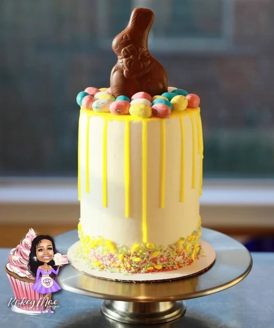 Easter bunny drip cake by Kakey Mae. Yellow drips, colorful candy eggs, and a chocolate bunny on a tall celebration cake.