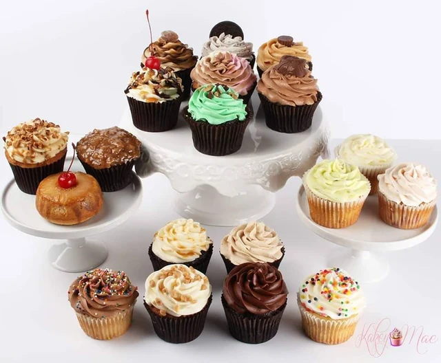 A dessert-table assortment by Kakey Mae. A variety of toppings and buttercream finishes presented together for a celebration.